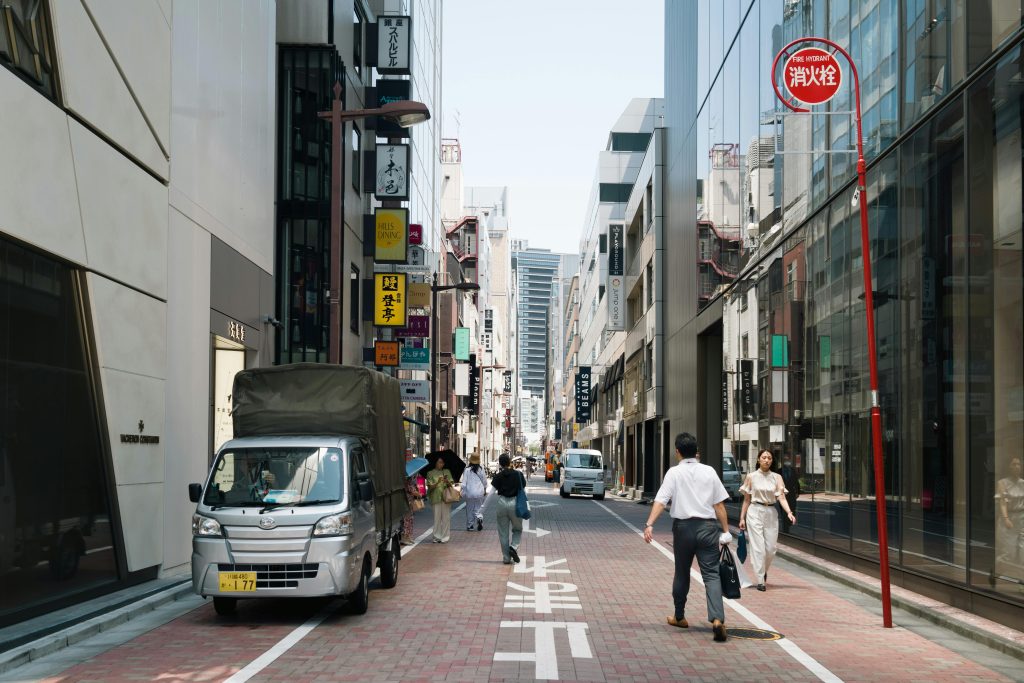 Street view of Chūō, Tokyo with people and vehicles on a sunny day.